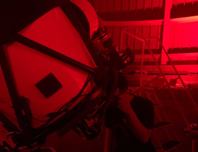 A person observing through a telescope in July 2021 at the 'Scopes at the Adler small-group experience inside the Adler Planetarium's Doane Observatory.