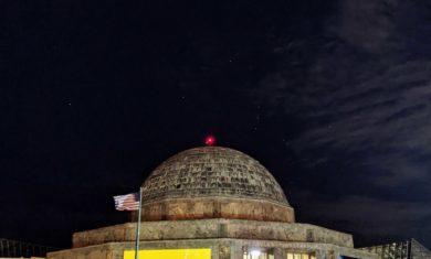 The Adler Planetarium at night with the constellation Orion shining in the sky.