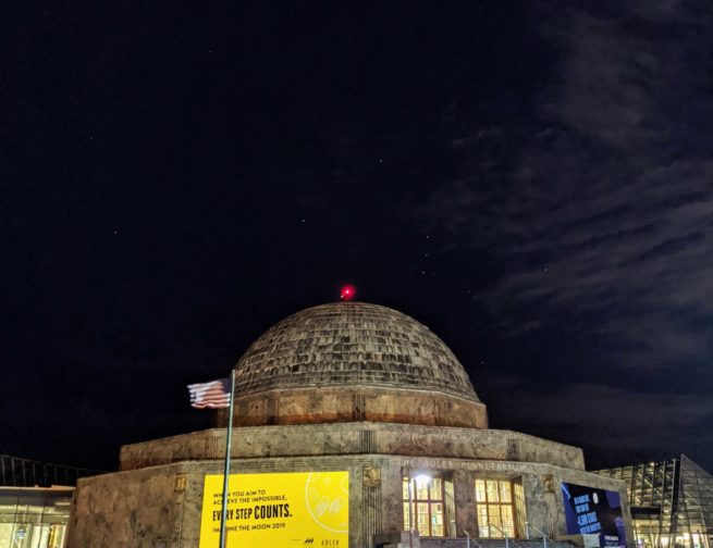 The Adler Planetarium at night with the constellation Orion shining in the sky.