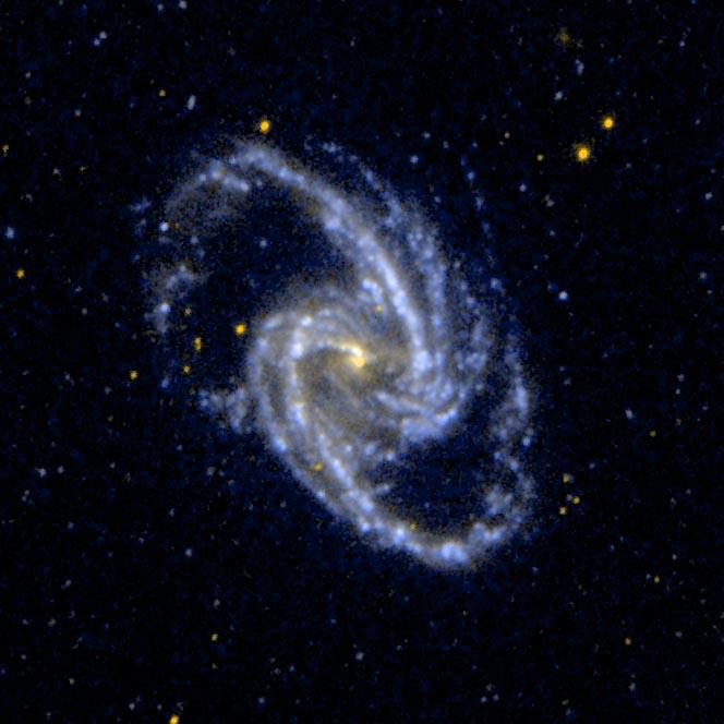 A spiral galaxy with a yellow dot in the center and blue and white dots spiraling out from the center
