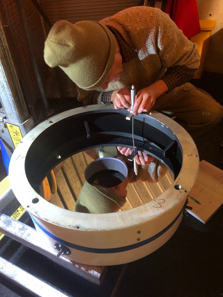 A volunteer from the Fox Valley Astronomical Society uses a micrometer to measure how level the edges of the telescope are.