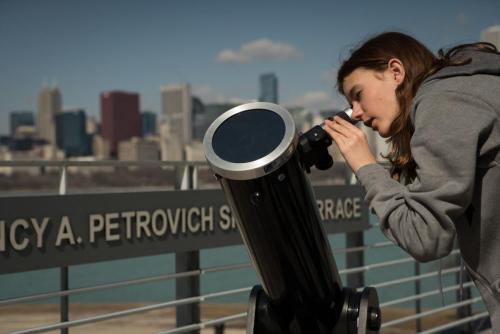 An image of a young girl telescope observing on the Adler's terrace.