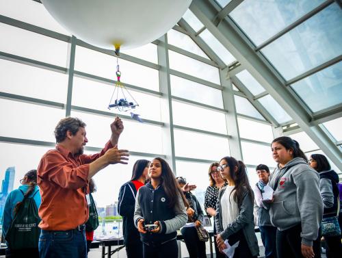 An image of a group of girls gazing at a high-altitude balloon while attending the Adler's "Women in Space Science" luncheon.