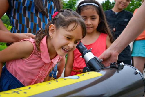 An image of a young girl peering through a telescope during one of the Adler's "Scopes in the City" events.