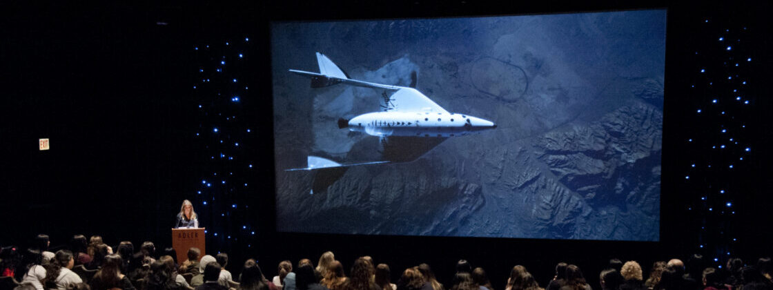 Crowd looking at presenter with large image of a rocket in the Johnson Family Star Theater.