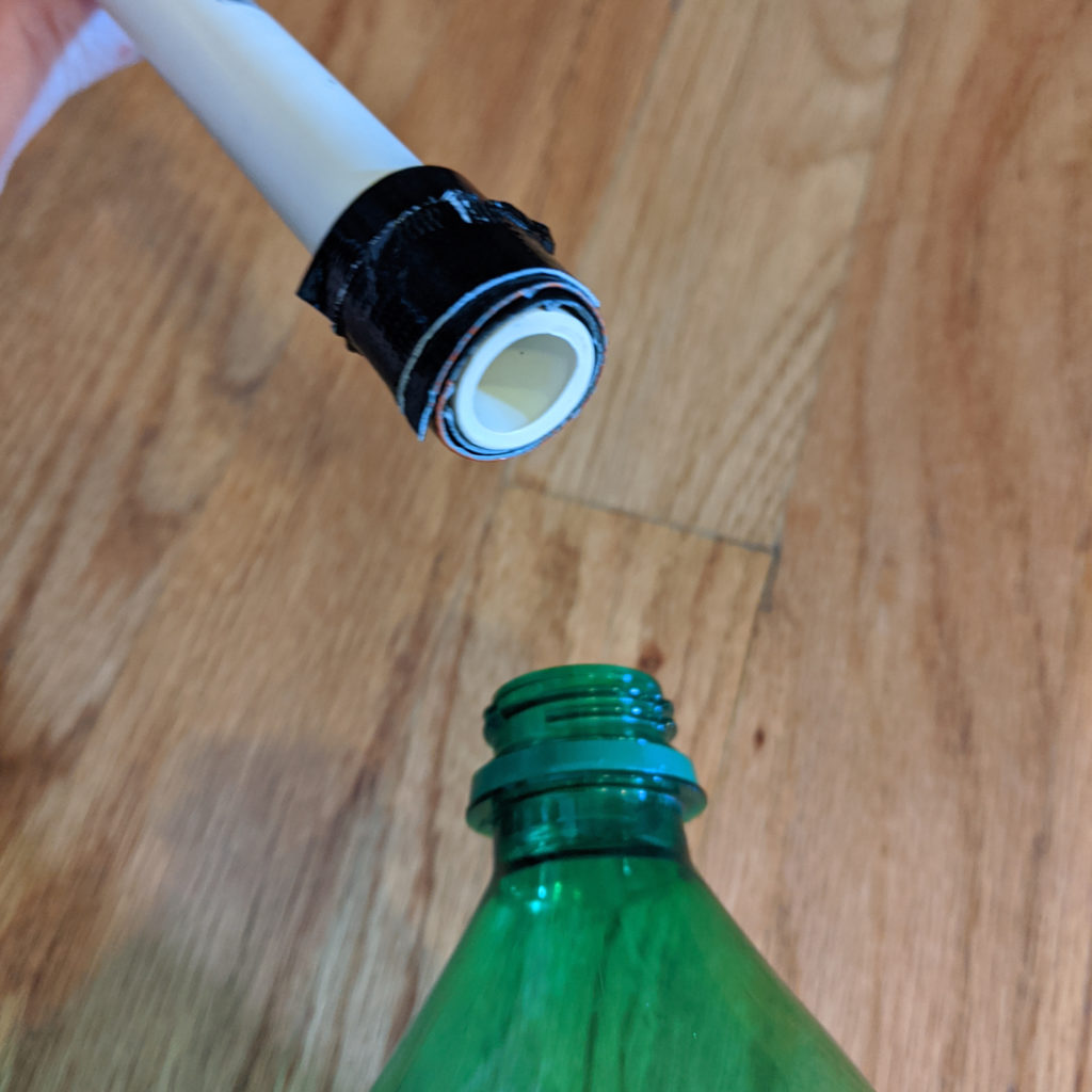 Wrap tape around the PVC pipe until it fits snugly inside of the bottle opening or PVC elbows