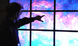 A guest points towards a video display of the cosmos.